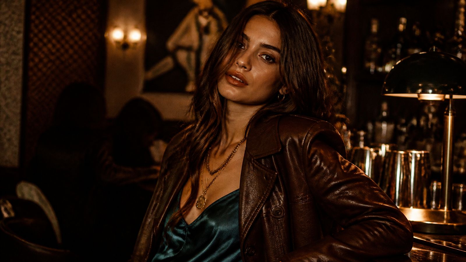 Young woman with dark auburn hair in a chocolate leather jacket and deep teal satin top, wearing Dark Autumn colors